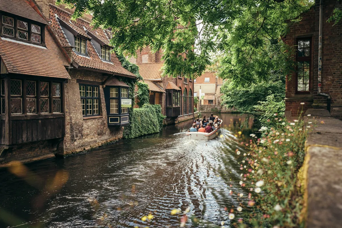 Un bateau touristique naviguant sur un étroit canal de Bruges