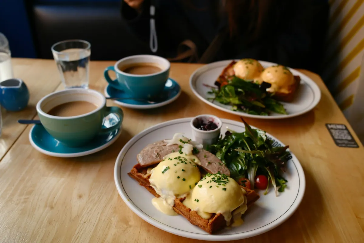 Two plates of eggs Benedict with salad at brunch