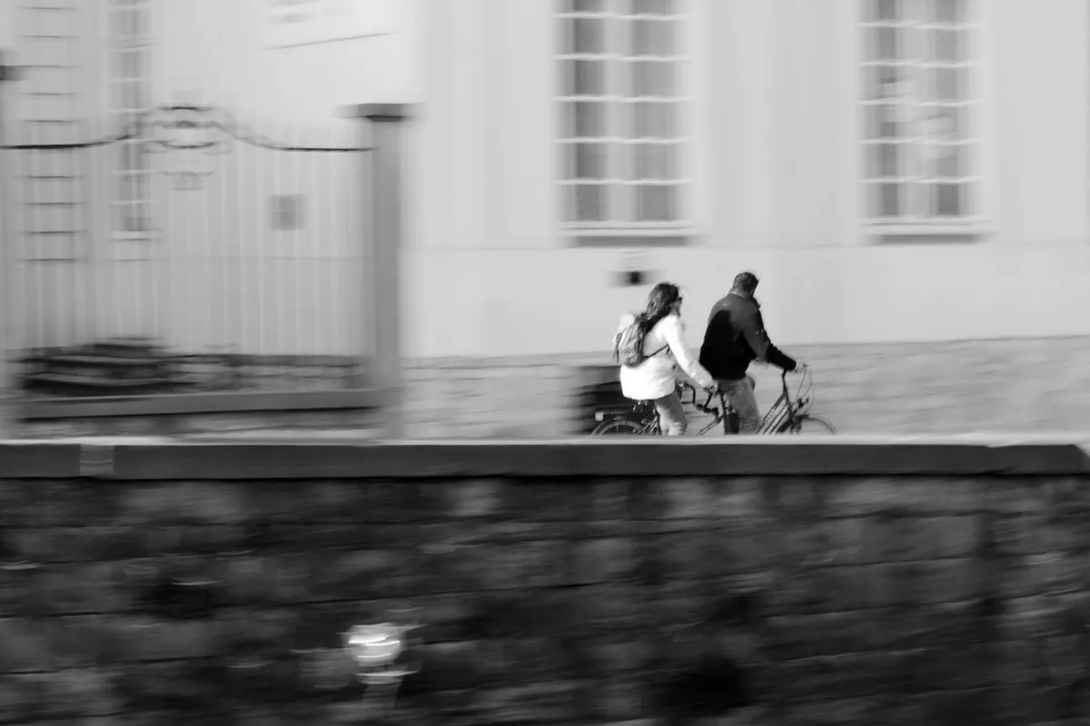 Cyclists riding a tandem beside a canal in Bruges